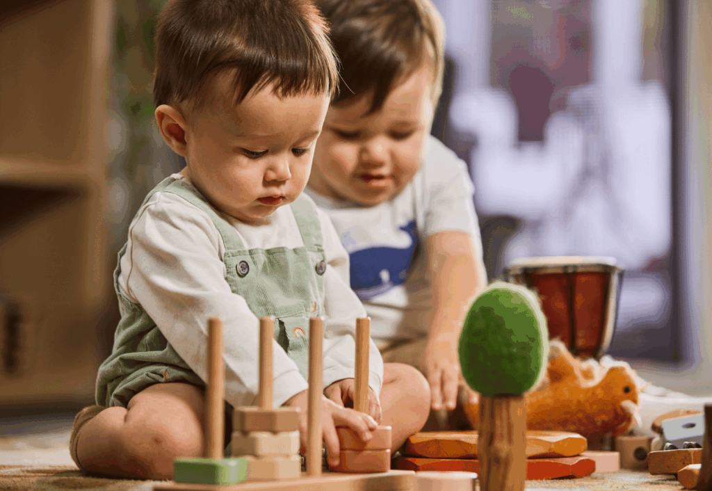 Toddlers exploring and learning through play with natural wooden toys in a bright early learning environment.